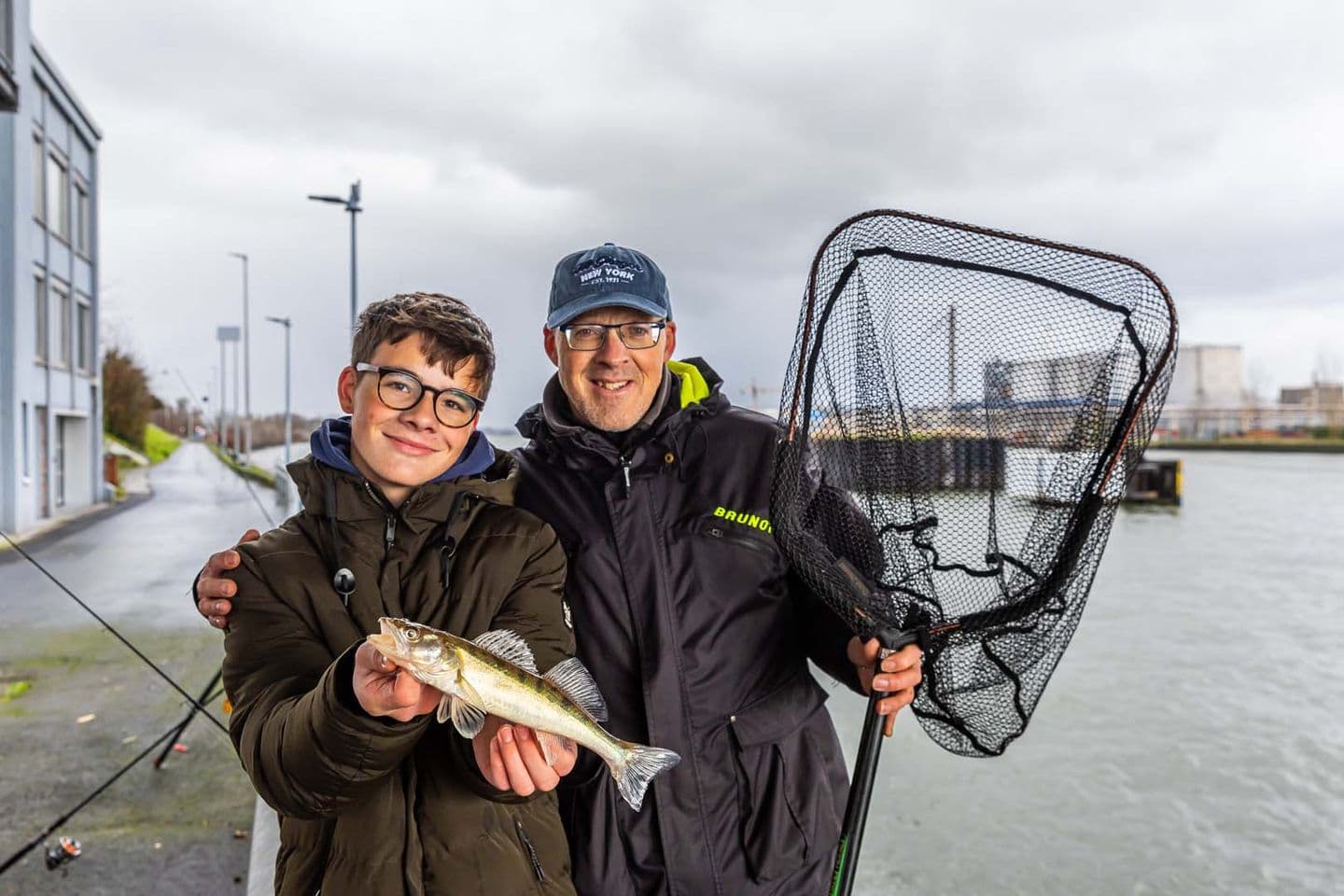 Vader en zoon vissen samen aan de waterkant